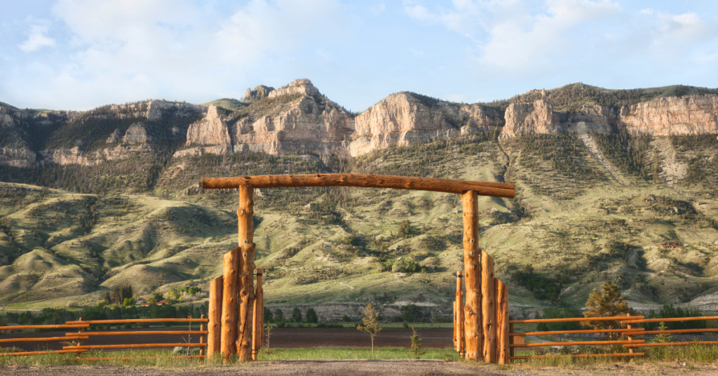 An image showing a custom ranch gate connected to a fence line at the entrance of a property in a desert setting.