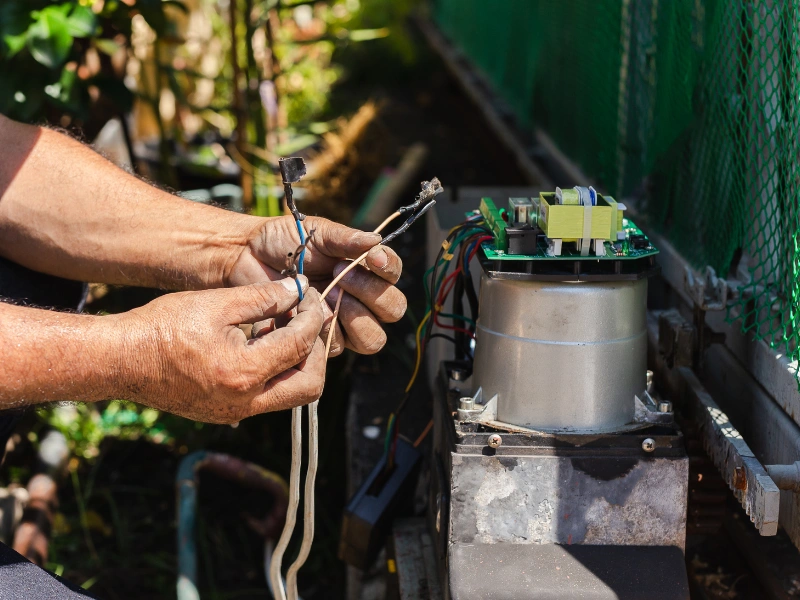 A professional automatic gate technician working on a Phoenix driveway gate.